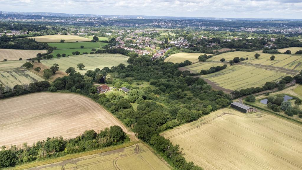 Lot: 105 - OVER NINE ACRES OF FREEHOLD GREENBELT LAND - Drone shot of land with Chigwell village in distance